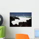 A wave breaks with lave rocks in the foreground Wall Mural