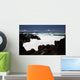 A wave breaks with lave rocks in the foreground Wall Mural