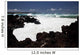 A wave breaks with lave rocks in the foreground Wall Mural