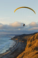Paraglider flying over ocean cliffs at sunset EDITORIAL USE ONLY Wall Mural