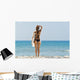 A woman wearing a black bikini stands Wall Mural