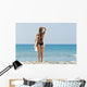 A woman wearing a black bikini stands Wall Mural