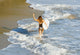 Woman running along beach with surfboard Wall Mural