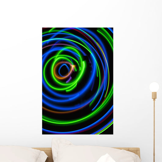 Silhouette of woman spinning hula-hoop lit with LEDs in field at night Wall Mural