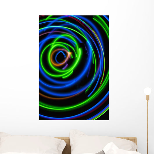 Silhouette of woman spinning hula-hoop lit with LEDs in field at night Wall Mural