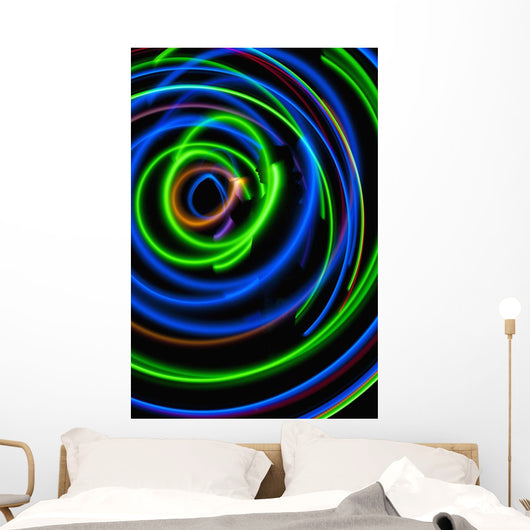 Silhouette of woman spinning hula-hoop lit with LEDs in field at night Wall Mural