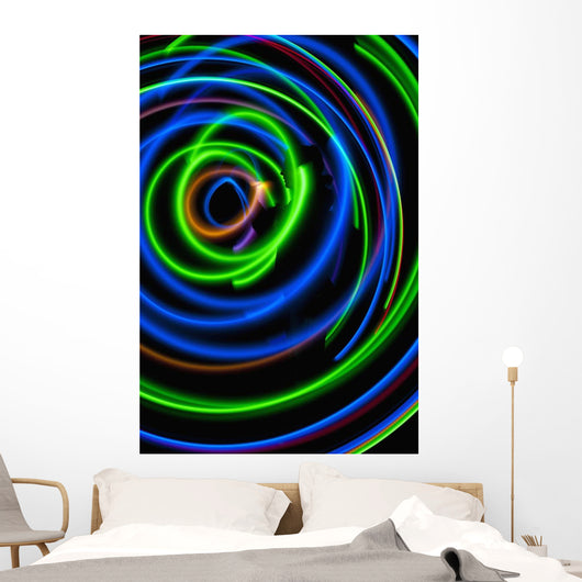 Silhouette of woman spinning hula-hoop lit with LEDs in field at night Wall Mural