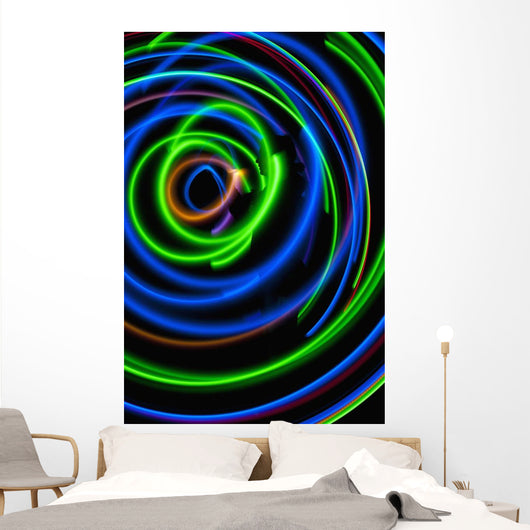 Silhouette of woman spinning hula-hoop lit with LEDs in field at night Wall Mural
