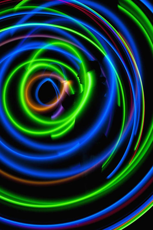Silhouette of woman spinning hula-hoop lit with LEDs in field at night Wall Mural