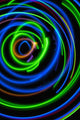Silhouette of woman spinning hula-hoop lit with LEDs in field at night Wall Mural