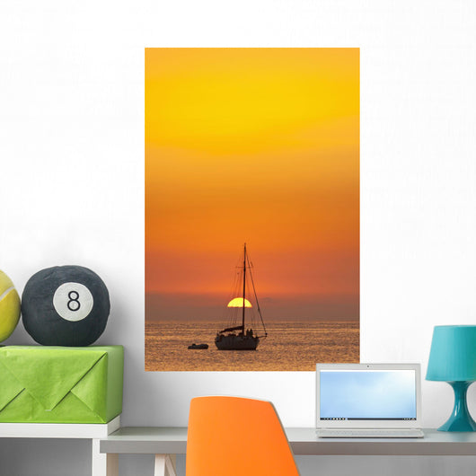 Spain, People watching sunset from yacht moored off Benirras beach Wall Mural