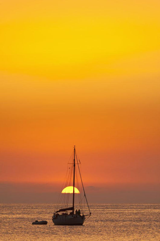 Spain, People watching sunset from yacht moored off Benirras beach Wall Mural