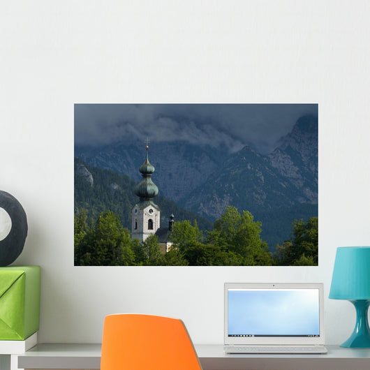 Germany, Stormy clouds behind Ruhpolding church Wall Mural