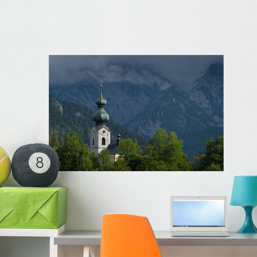 Germany, Stormy clouds behind Ruhpolding church Wall Mural