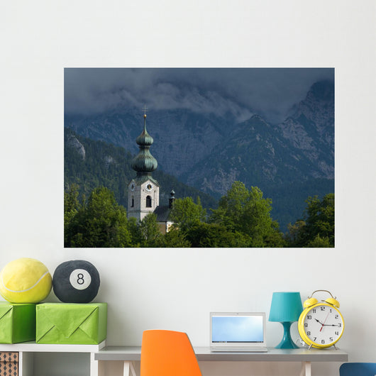 Germany, Stormy clouds behind Ruhpolding church Wall Mural