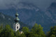 Germany, Stormy clouds behind Ruhpolding church Wall Mural