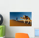 Berber leading camel across sand dune near Merzouga in Sahara Desert Wall Mural