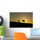 Silhouette of Berber 'Blue man' leading camel across sand dunes Wall Mural