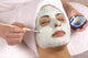 spa esthetician applying facial masque Wall Mural