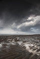 Rippled sand under a dark cloud Wall Mural