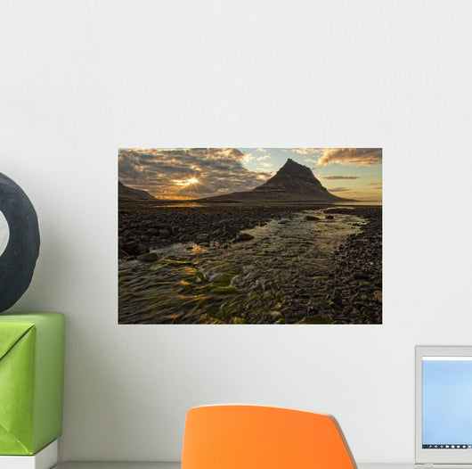 The mountain Kirkjufell rises above the ocean as the sun sets Wall Mural