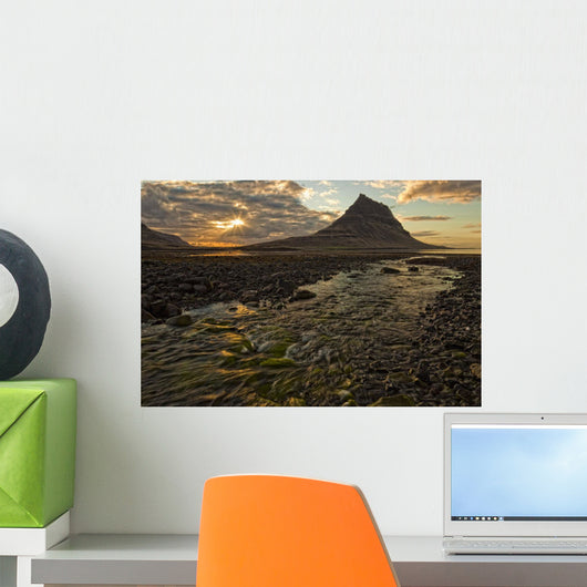 The mountain Kirkjufell rises above the ocean as the sun sets Wall Mural