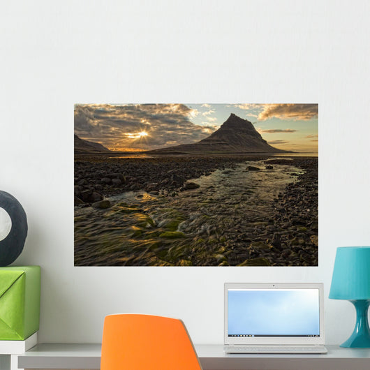 The mountain Kirkjufell rises above the ocean as the sun sets Wall Mural