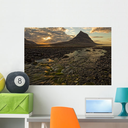 The mountain Kirkjufell rises above the ocean as the sun sets Wall Mural