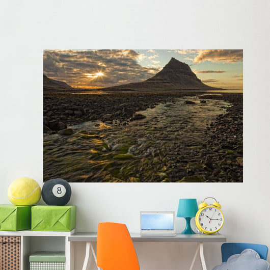 The mountain Kirkjufell rises above the ocean as the sun sets Wall Mural