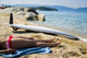 Young woman sunbathing on beach with surf board on sand Wall Mural