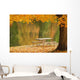 A picnic table beside a tranquil lake with golden leaves on the trees Wall Mural