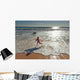 Woman in wetsuit running on beach Wall Mural