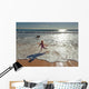Woman in wetsuit running on beach Wall Mural