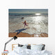 Woman in wetsuit running on beach Wall Mural
