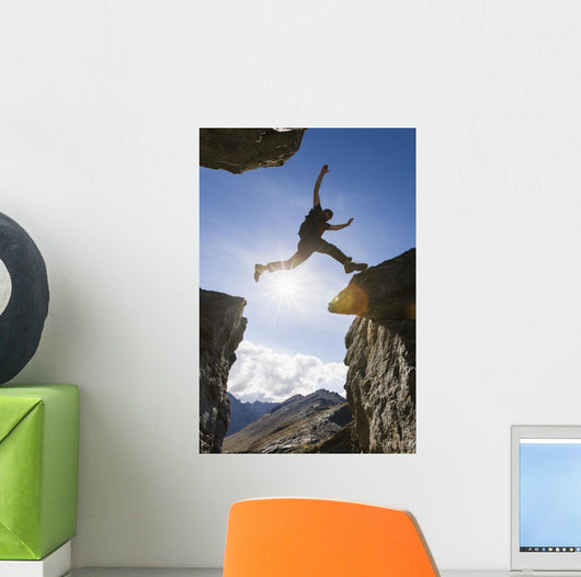 Backlit View Of Hiker Leaping Between Rocks Near Noatak River Wall Mural
