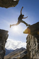 Backlit View Of Hiker Leaping Between Rocks Near Noatak River Wall Mural