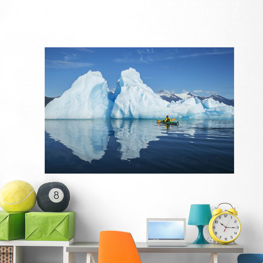 A Sea Kayaker Paddles Beside An Iceberg Wall Mural