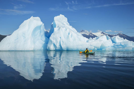 A Sea Kayaker Paddles Beside An Iceberg Wall Mural
