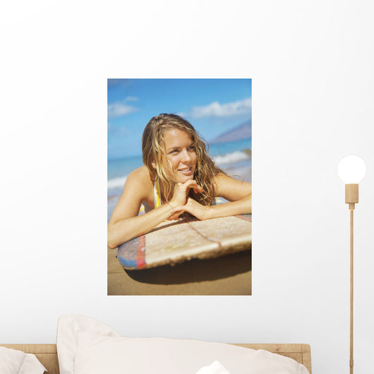 A Young Woman Lays On A Surfboard On The Sand Wall Mural