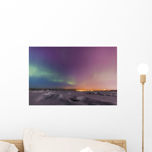 Northern lights shine above city skyline in this nighttime view Wall Mural
