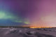 Northern lights shine above city skyline in this nighttime view Wall Mural