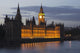 A Building And Clock Tower Along The Water's Edge Illuminated At Dusk Wall Mural