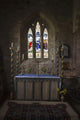 Stained glass windows and a table surrounded with candles in a church Wall Mural
