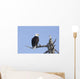 An eagle up on the top of a dead tree against a blue sky Wall Mural