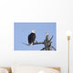 An eagle up on the top of a dead tree against a blue sky Wall Mural