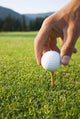 Golfer sets up a ball on the tee of a golf course on a summer evening Wall Mural