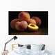Peaches sitting on a wooden table, one cut in half Wall Mural