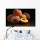 Peaches sitting on a wooden table, one cut in half Wall Mural