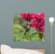 A hummingbird hovers by a bright pink blossoming flower Wall Mural