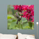 A hummingbird hovers by a bright pink blossoming flower Wall Mural